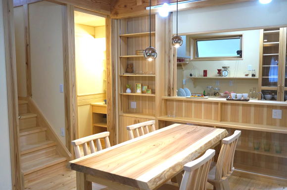 対面キッチンカウンター収納とリビング階段。ダイニングテーブルは秋田杉の銘木で制作したテーブル